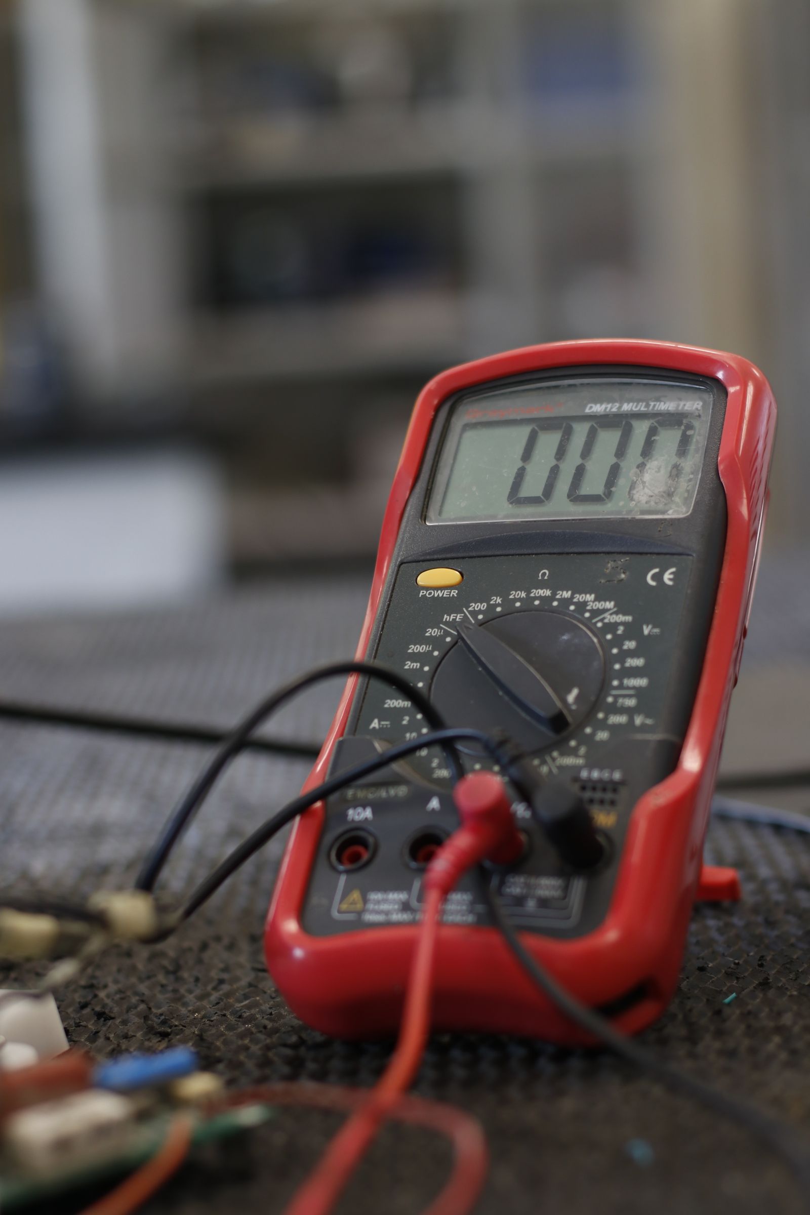 Close-up of a digital multimeter and test leads on a workbench